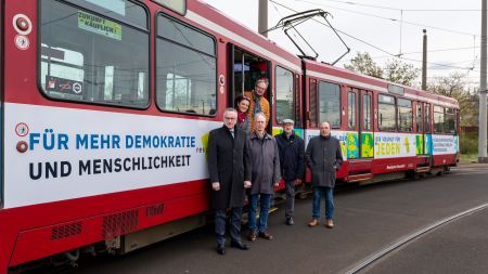 Vertreter:innen des Netzwerks "Respekt und Mut" stehen vor der Straßenbahn