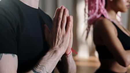 Vor der Brust aufeinanderliegende Handflächen während Meditation