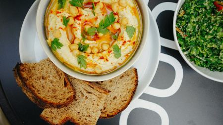 Humus und Tabouleh in Schüsseln angerichtet, dazu Brot