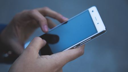 Person hält Handy in beiden Händen