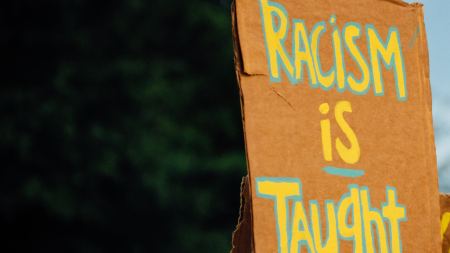Pappschild mit Aufschrift "Racism is taught"