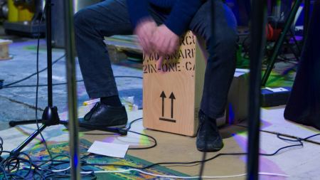 Person sitzt auf einer Cajon und spielt