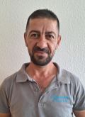 Portrait von Komat Ali Jangir: Mann mit dunklen kurzen Haaren, kurzem Bart und braunen Augen trägt ein graues Poloshirt mit der blauen Aufschrift "Multikulturelles Forum e.V."